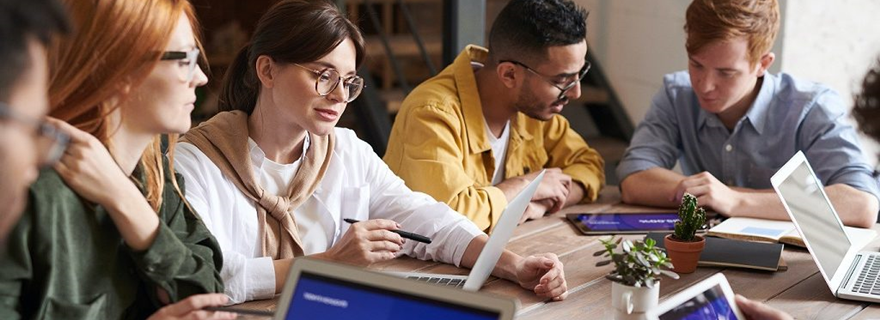 Gruppe von jungen arbeitenden Menschen mit Laptops in einem Shared Office